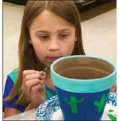 Anna Johnson, daughter of Joy Johnson, granddaughter of Dan and Susan Simmons, is shown working on a flower pot. Article Image Alt Text