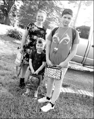 Jozie, fifth grade, Cameron, kindergarten, and Rylea, sixth grade, get in a first day of school photo before being dropped off at their respective Atlanta ISD school. Article Image Alt Text