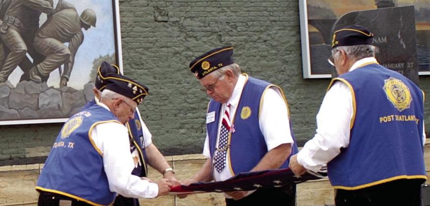 On a recent Memorial Day, flags which had flown above Veterans Plaza in downtown Atlanta were lowered and changed for new ones. Folding one of the flags are members of the J.E.Manning American Legion Post 258.From left, they are Mike Steward, Bob Steger, Article Image Alt Text