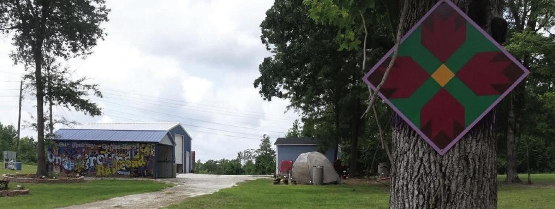 The entry way to the “Last Railway Station” property display belonging to Sharon Haynes on 3077 FM 1399 just north of the Pleasant Hill church and school.The paintings by artist James Coleman are on the sides of large truck trailers and buildings.