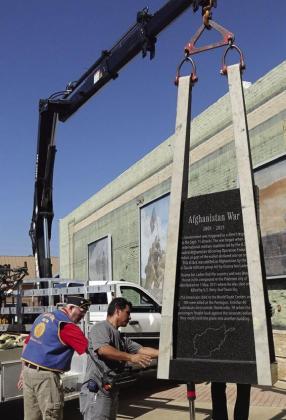 The strength and balance of lowering a 450-pound base and 750-pound slab is shown in this photograph. Atlanta legion member Gary Richardson is helping the West Memorials employee place the Afghanistan monument.