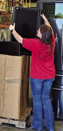 Olivia Beauchamp places an e-waste television into a box. Olivia Beauchamp places an e-waste television into a box.