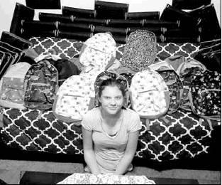 Savannah sitting with some of the backpacks she will be handing out on Aug. 3. Article Image Alt Text