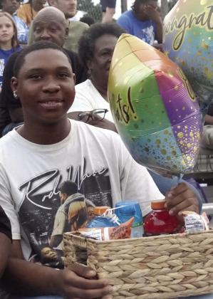 Kortin Mack is holding a box full of treats and a congratulatory balloon as a reward for his sister Ja’Maiya Mack who happens to be out on the field as a member of the homecoming court and soon to be announced queen.