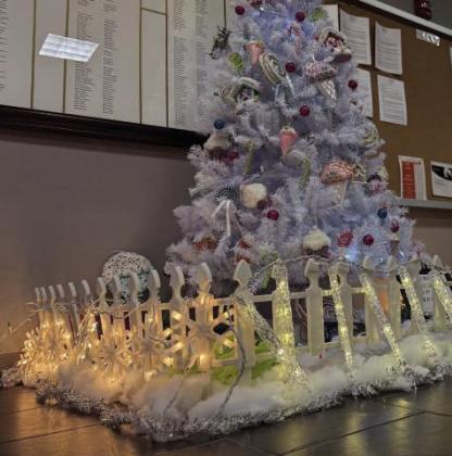 A lighted fence sets off a beautiful white Christmas tree.