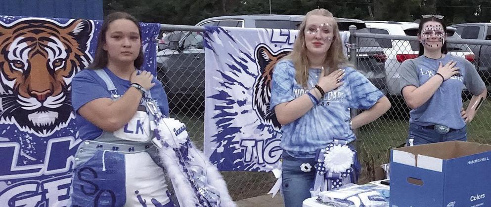 The national anthem is being played before the start of the Linden-Kildare football game last Friday, and so its hands over hearts for these students of Linden-Kildare who are selling gift school gift items to the public.