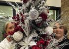 Atlanta Auxiliary volunteers,Judy Coolidge,left,and Susy O’Kelley are partially hidden as they stand behind the Christmas tree they themselves have decorated for the auxiliary’s silent auction. CHRISTMAS TREE AUCTION