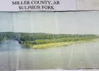 Looking from the Arkansas Highway 160 bridge northward, one sees the fork of the Sulphur River on the left coming from Texas and the Red River on the right going up into Arkansas. This wide photo is on the shelf in the Genealogical Society’s floor at th River Confluence