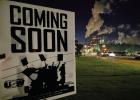 USW Union sign sticks out of the grass along the highway in the early morning hours as lights and smoke ominously illuminate the front of the Graphic Packaging paper mill in Domino. The sign says “Coming Soon” with images of picketers coming together 