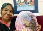 Holding one of her striking works with a second on the wall in the background is senior student December Soria. December is one of the featured artists in the current show. Art Show Closes Tomorrow