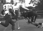 Trenton Belk for Queen City (in black) looks as if he is about to go down, but he catches the ball and breaks away for an opening first period, first play of the game touchdown.